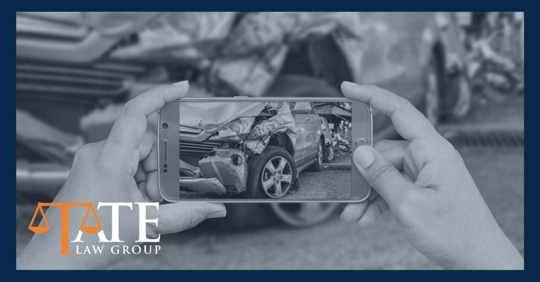 Woman holding a cell phone taking a picture of a crashed car.