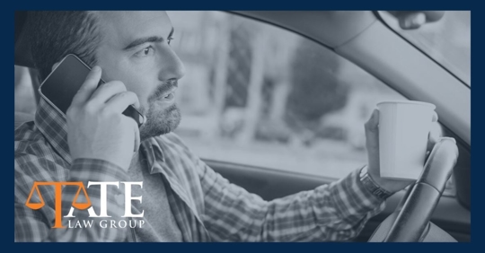 Man on cell phone talking and his hand on the steering wheel holding a cup of coffee.